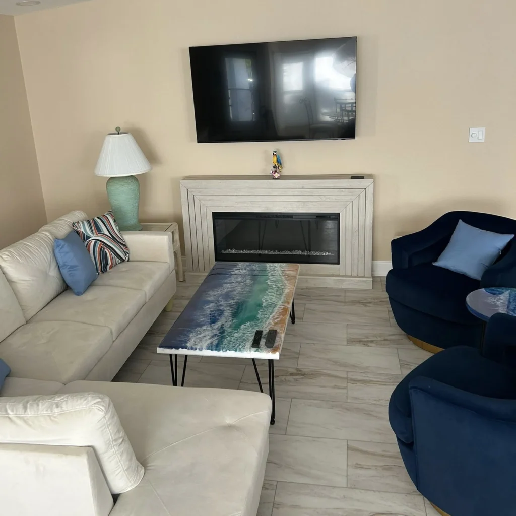 Living room renovation involving a white couch, two dark blue chairs, and a fireplace carried out by Regalbuto Contractors