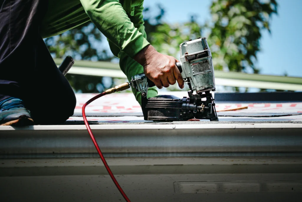 Roofer using nailgun on roof representing roofing services for Regalbuto Contractors