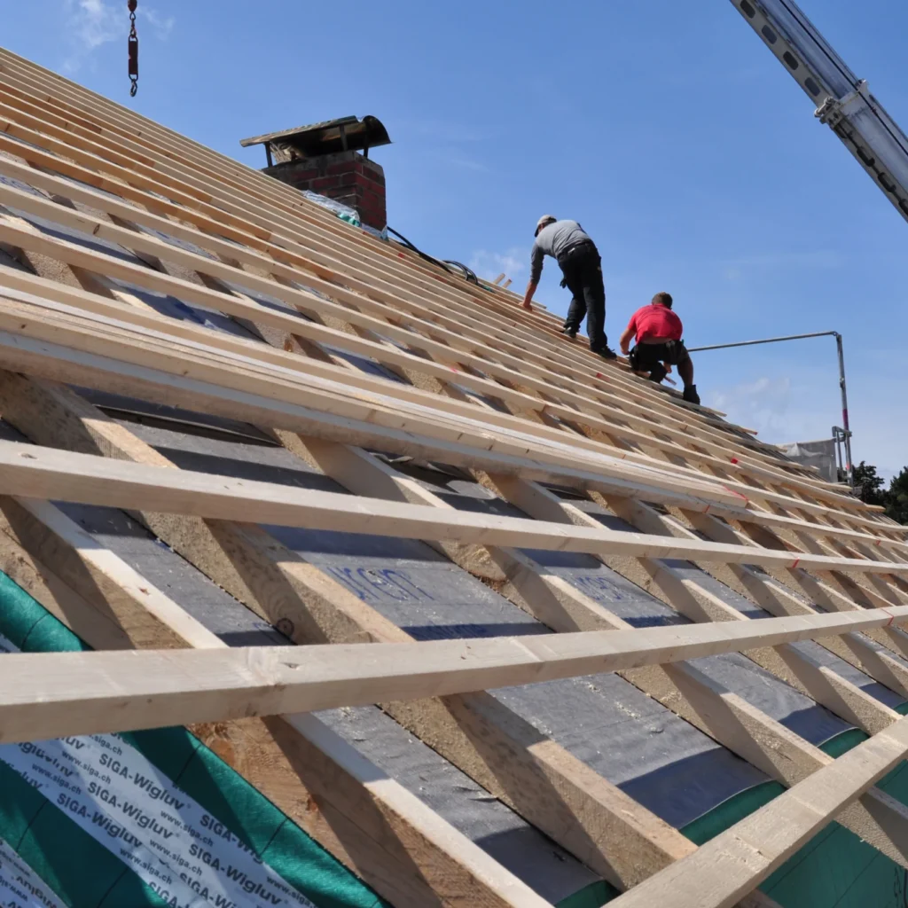 Builders installing new roof while standing on roof scaffolding