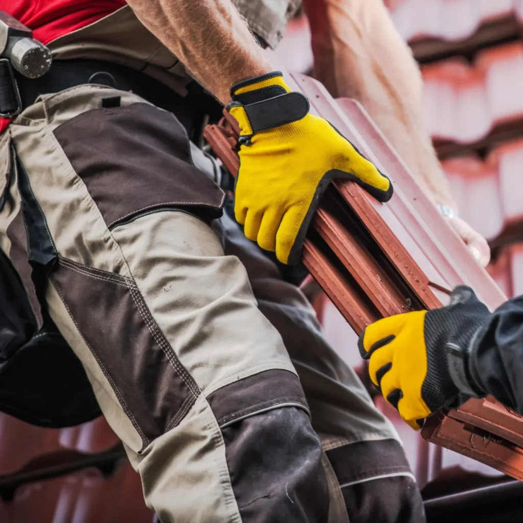 Workers handing roof tiles to each other in the middle of a build